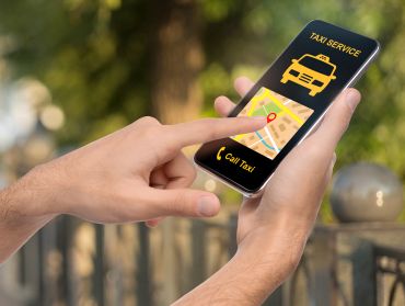 Man holding smartphone with taxi app interface